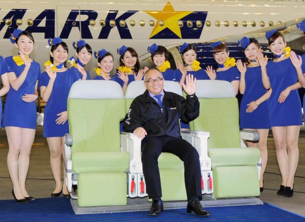 Shinichi Nishikubo, presidente de Skymark Airlines Inc. posa junto con su personal demostrando la comodidad de los asientos del Airbus 330